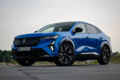 Niebieski Renault Rafale, SUV coupe, zaparkowany na drewnianym tarasie.
