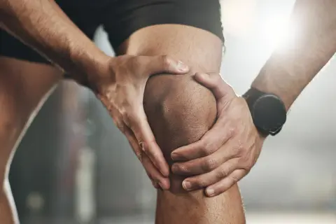 Sportler hält schmerzendes Knie. Möglicher Kreuzbandriss? Ein Selbsttest kann erste Hinweise geben.