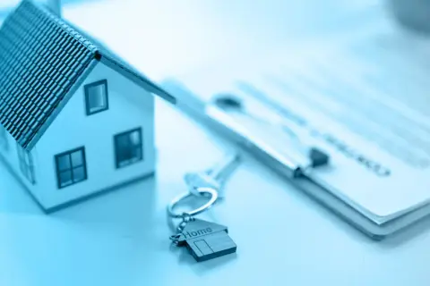 Modellino di casa, chiavi con ciondolo a forma di casa e documenti pronti per vendere casa.