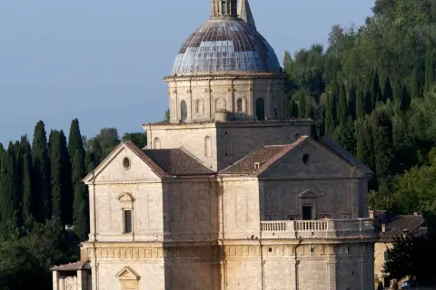Il tempio di San Biagio, con la sua imponente cupola e la facciata in pietra, si erge maestoso tra i cipressi toscani.