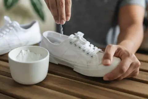 Un rimedio naturale per come togliere puzza dalle scarpe: bicarbonato versato dentro una scarpa bianca.