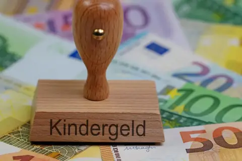 Stempel z napisem "Kindergeld" na tle banknotów euro. To symbol wsparcia dla rodzin, jak 500+.