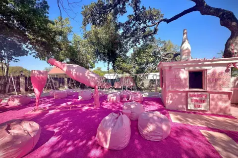Różowa strefa relaksu z gigantyczną butelką i kieliszkiem prosecco rose, gdzie można usiąść na pufach i napić się różowego napoju.