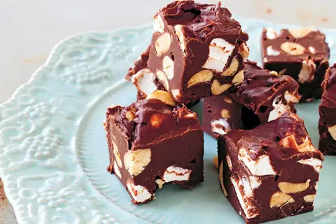Chokladbitar med marshmallows och nötter, en härlig rocky road-fudge på en ljusblå tallrik.