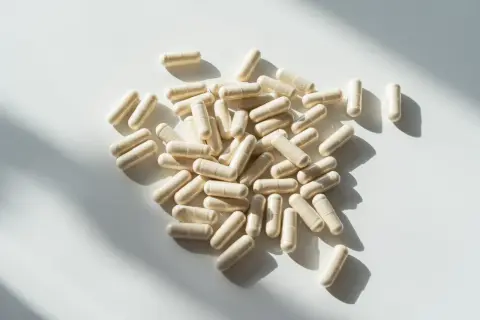 Kapsułki probioset rozsypane na białym tle, oświetlone słońcem.