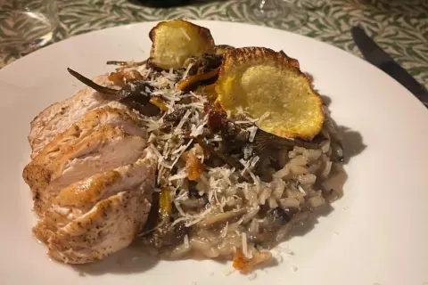 En härlig tallrik med tryffelrisotto med kyckling, toppad med krispiga potatisskivor och riven parmesan. En riktig smakupplevelse!