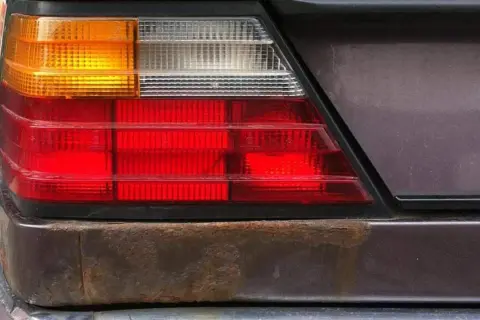 Rost unter Lack am Heckleuchtenbereich eines Autos. Zeit, den Rost unter Lack zu entfernen und das Fahrzeug zu retten.