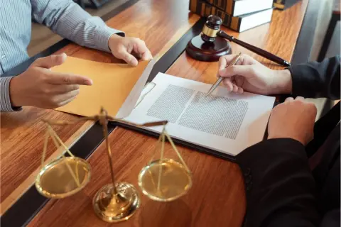 Prawnik doradza, jak wybrnąć ze skargi pauliańskiej. Na stole dokumenty, waga sprawiedliwości i młotek sędziowski.