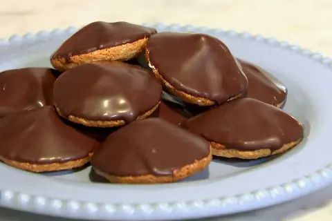 En hög med chokladöverdragna biskvier på en ljusblå tallrik. Perfekt för ett enkelt biskvier recept.