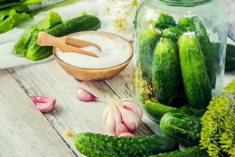 Świeże ogórki, czosnek, koperek i miseczka z solą – idealne składniki, by przygotować pyszne ogórki małosolne. Jaka sól do ogórków małosolnych? Drobna, niejodowana!