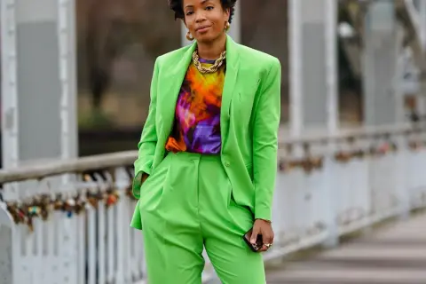 Donna con completo verde brillante, maglia tie-dye e collana dorata. Un look che celebra l'armocromia primavera con colori vivaci.