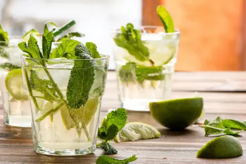 Verre de mojito frais avec menthe, citron vert et glaçons. Parfait pour une recette mojito rafraîchissante.