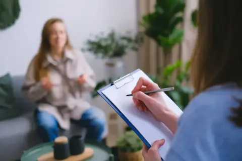 Psycholog policyjny zarobki: sesja terapeutyczna z pacjentem, notatki na kartce.