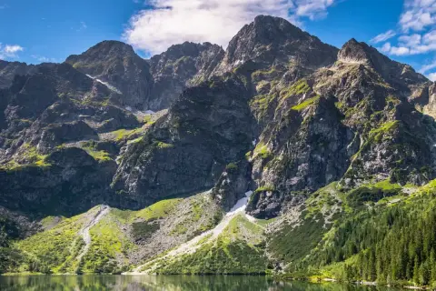 Majestatyczne, najwyższe góry w Polsce Tatry, odbijające się w spokojnej tafli jeziora.