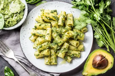 Makaron z pesto ze słoika, podany na talerzu, z awokado i świeżymi ziołami.
