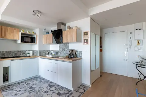 Cuisine 10m2 fermée, moderne et fonctionnelle avec placards blancs, carrelage géométrique et plan de travail en bois.