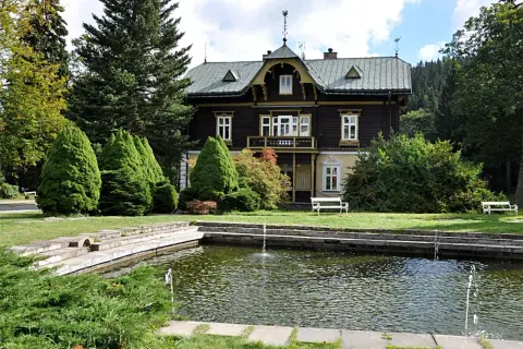 Urokliwy dworek w Karlovej Studance z basenem i fontannami, otoczony zielenią.