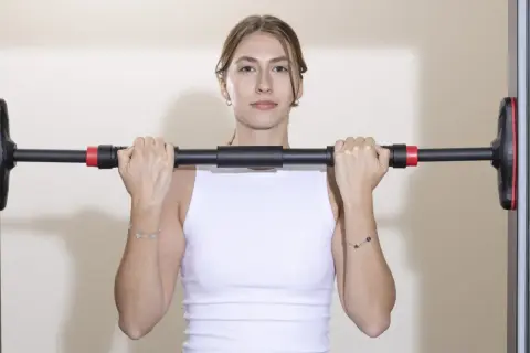 Frau hält Klimmzugstange Türrahmen Test. Einfache Montage für das Training zu Hause.