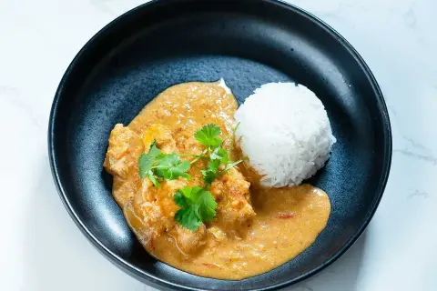En krämig butter chicken med ris, garnerad med färsk koriander. En smakrik indisk rätt.