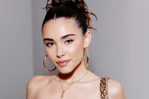 Mujer con un peinado recogido y grandes aretes dorados, luciendo un **clean look** que resalta su belleza natural.