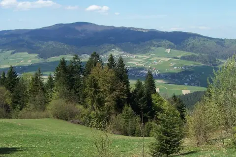 Zielone wzgórza i lasy Gorczańskiego Parku Narodowego, z widoczną w oddali wioską.