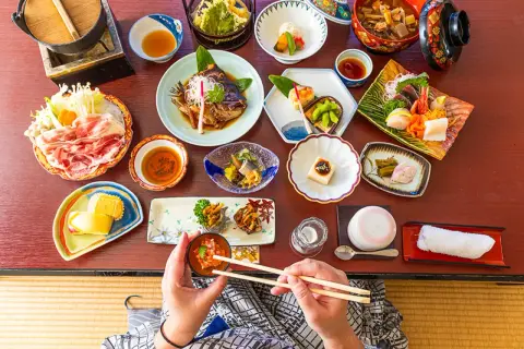 Un festin de street food japonais : sashimi, poisson grillé, tofu, et bien plus encore, présenté avec art sur une table en bois.