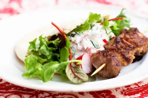 Saftiga kebabspett i ugn serveras med pitabröd, fräsch sallad och en krämig yoghurtsås med rädisor. En perfekt middag!