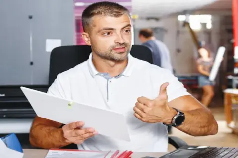 Mężczyzna z dokumentem i kciukiem w górze, pokazujący jak znaleźć kod PKD.