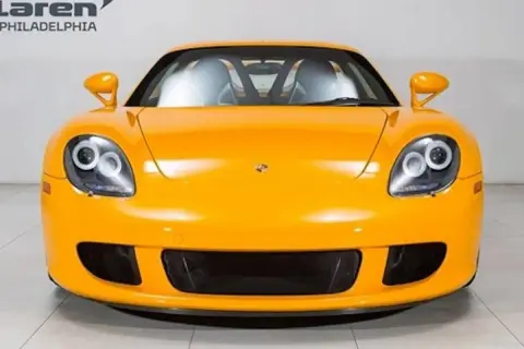 Pomarańczowy Porsche Carrera GT z charakterystycznymi okrągłymi światłami i sportowym grillem.