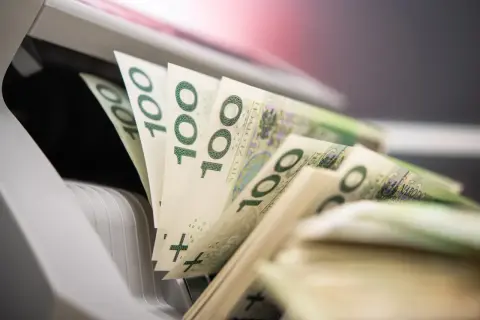 Stos banknotów 100 zł w maszynie do liczenia pieniędzy.