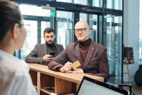 Mężczyzna z kartą w ręku, spełniający wymagania private banking, czeka przy ladzie.