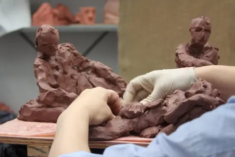Hands sculpt clay figures, a glimpse into the dedication needed for the best sculpture schools.