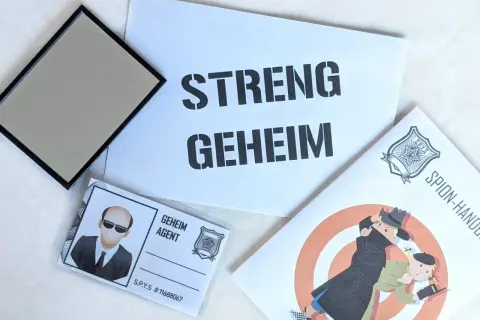 Spannende Detektiv Geburtstag Ideen: Ein Spiegel, ein Ausweis als "Geheim Agent" und eine Broschüre mit dem Titel "Spion-Handbuch" versprechen einen geheimen Missionstag.