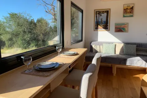Intérieur d'une tiny house dans les Landes, avec un coin repas face à la nature et un canapé confortable.