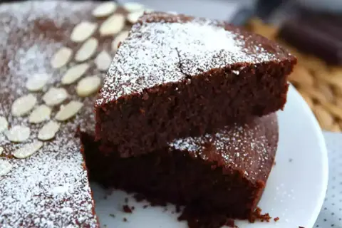 En saftig torta caprese, pudrad med florsocker och garnerad med mandelspån. En dröm för chokladälskare!