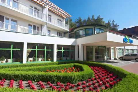 GeoVita Dąbki cennik: nowoczesny budynek hotelowy z zadbanym ogrodem i kwiatami.
