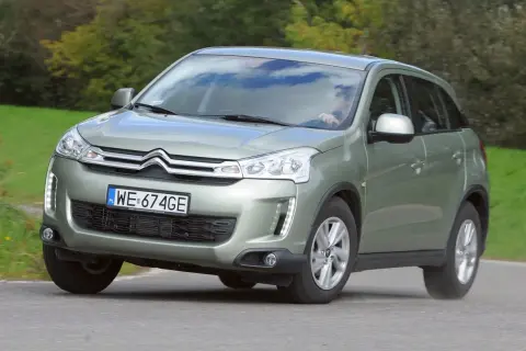 Zielony Citroen C4 Aircross z polskimi tablicami WE 674GE jedzie po drodze wśród zieleni.