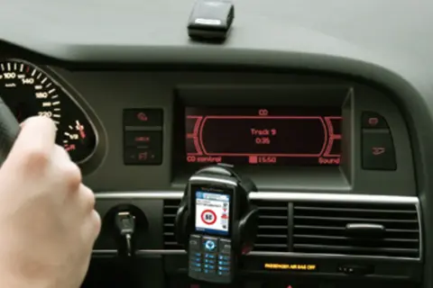 Ręka na kierownicy, telefon z nawigacją i ekran radia w samochodzie. Czy to podpowiedź, jak odkodować radio?