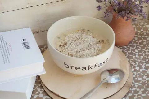 Misternie przygotowana owsianka na śniadanie, a obok książka. Czy płatki owsiane mają gluten? To pytanie nurtuje wielu.
