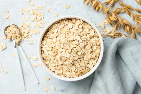 Misternie ułożone płatki owsiane w misce i na łyżce. Czy płatki owsiane mają gluten? Zwykłe płatki owsiane nie zawierają glutenu, ale mogą być zanieczyszczone podczas przetwarzania.