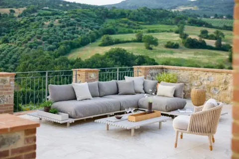 Eine stilvolle Dachterrasse gestalten: Gemütliche Lounge-Möbel mit Blick auf grüne Hügel laden zum Entspannen ein.
