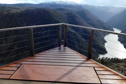 Mirador de Santiorxo con vistas a un río serpenteante entre montañas boscosas y picos nevados.