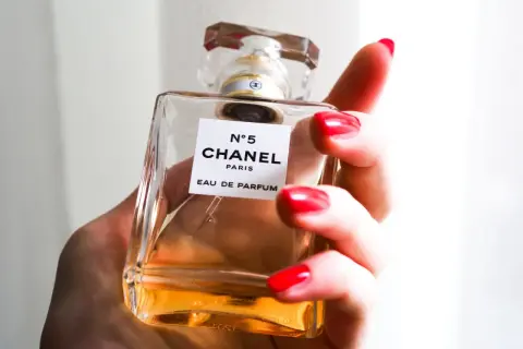 Dłoń z czerwonymi paznokciami trzyma flakonik Chanel N°5 100ml.