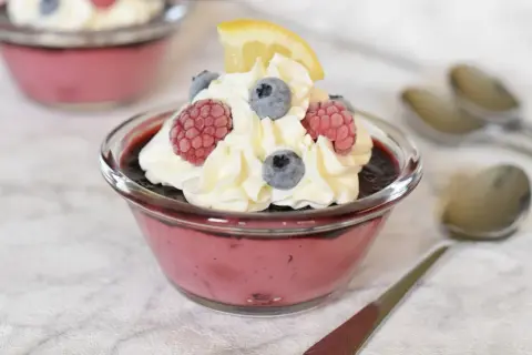 En krämig dessert med bär och mascarpone, toppad med vispgrädde, hallon, blåbär och en citronskiva. Perfekt att baka till fikat!
