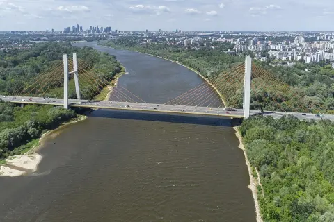 Most Siekierkowski w Warszawie nad Wisłą, z widokiem na panoramę miasta i zielone brzegi.