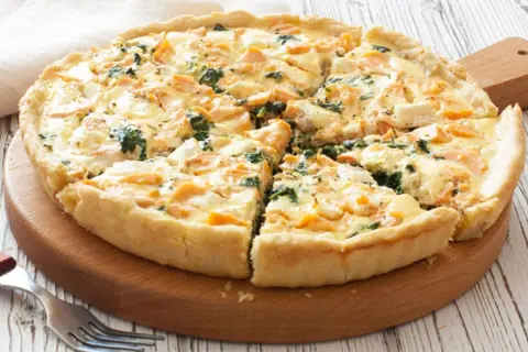 Tarta de espinacas y salmón, recién horneada y cortada en porciones, lista para disfrutar.