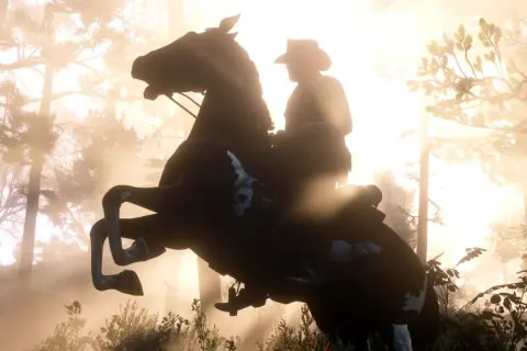 Jeździec na koniu wznoszącym się na tylne nogi, w lesie o wschodzie słońca. Niesamowita grafika z Red Dead Redemption 2 PS5 60fps.
