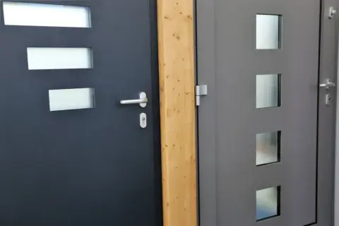 Dwie nowoczesne drzwi wejściowe, ciemnoszare i szare, z przeszkleniami. Dowiedz się, jak uszczelnić drzwi wejściowe, by zapewnić komfort.