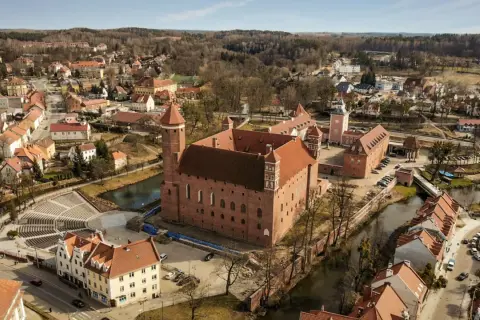 Lidzbark Warmiński atrakcje: imponujący zamek biskupów warmińskich otoczony fosą, malownicze miasteczko z czerwonymi dachami i amfiteatr.