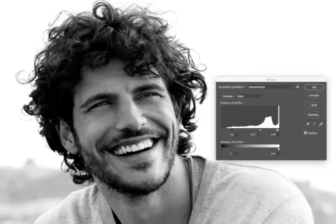 Portrait en noir et blanc d'un homme souriant, ajustant les niveaux dans Photoshop pour un rendu parfait.